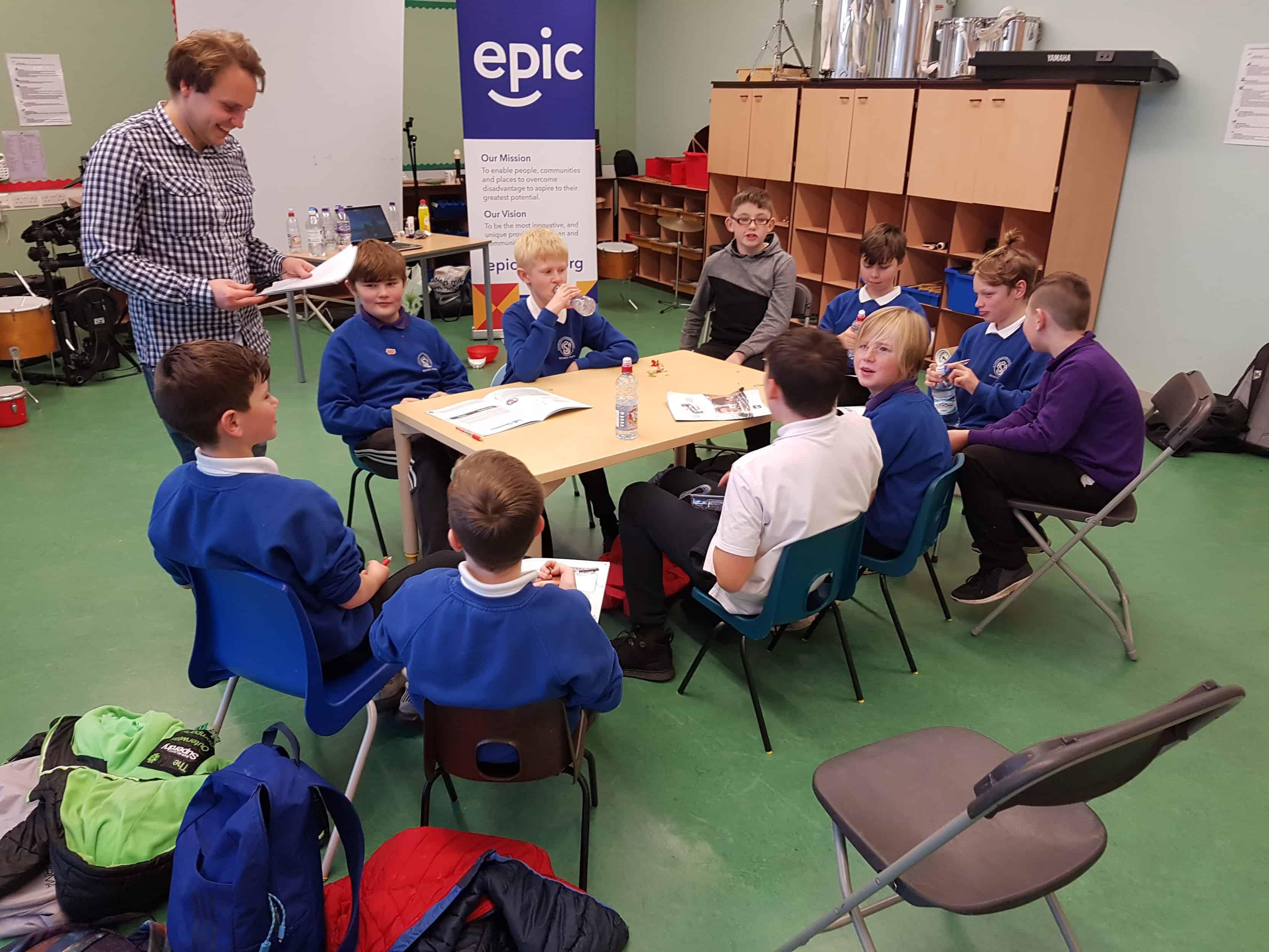 A group of boys from the Tranent Boys Project sit around a table working through booklets.